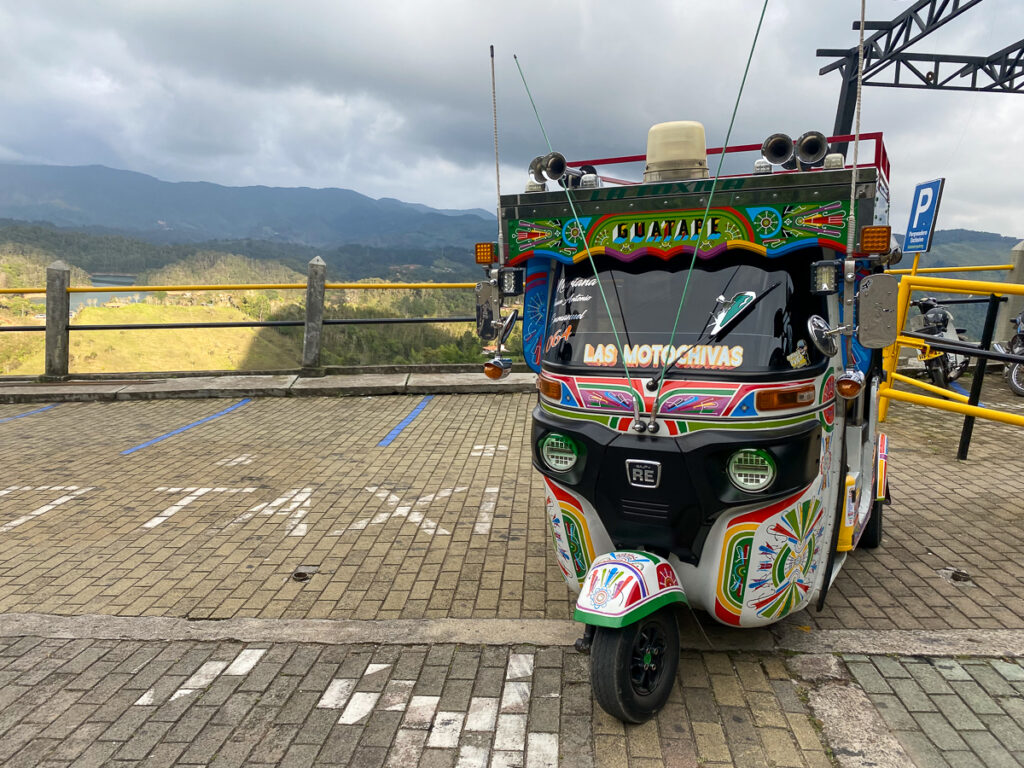 Colorful tuk tuk parked by a viewpoint. Going on a guided tuk tuk tour is one of the exciting things to do in Guatape if you want to explore more of its town.