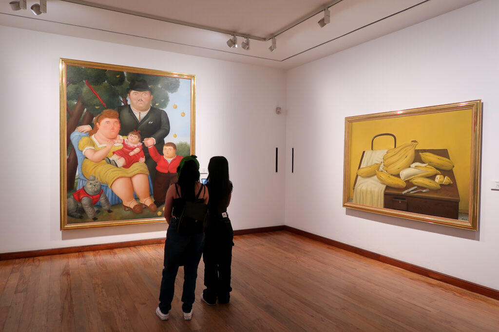 Two teenagers admiring the paintings at Museo Botero. Visiting the Botero Museum is one of the top things to do in Bogota, Colombia.