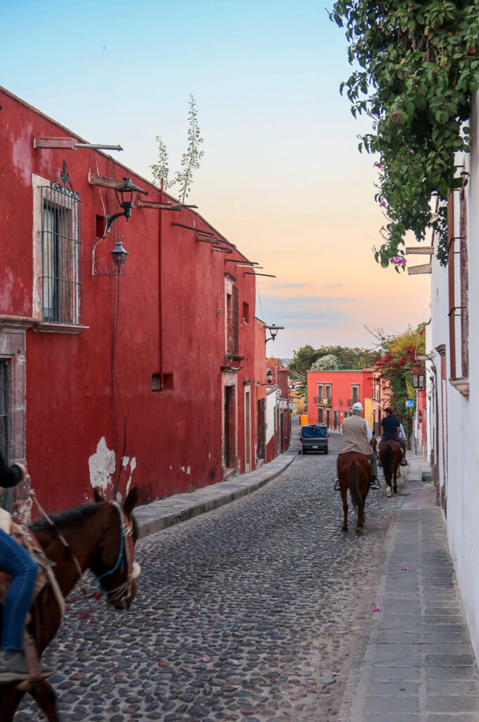 Group of people on horses galloping on the streets of San Miguel de Allende