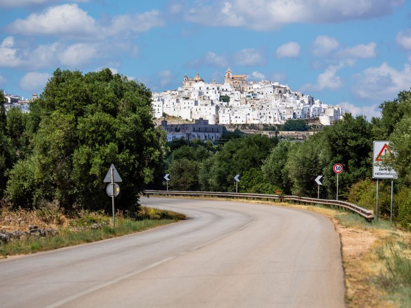 Curved road with the view of the hilltop town of Ostuni from afar