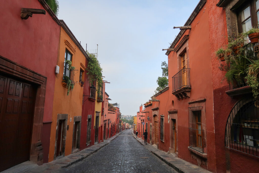 Red and yellow houses lining the quaint cobblestone street in San Miguel de Allende