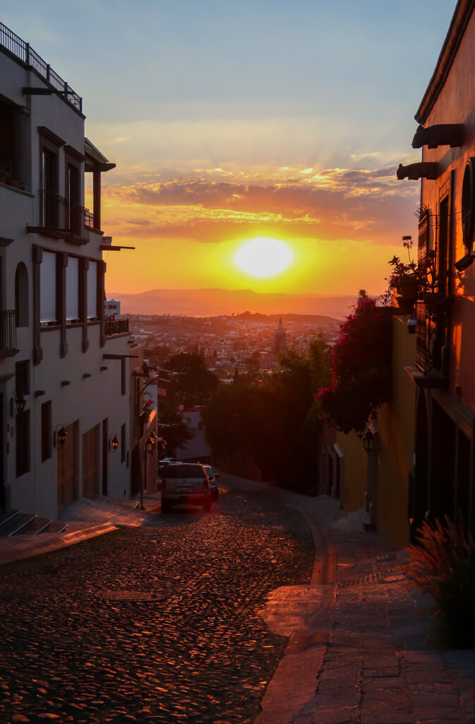 A downhill cobblestone street at sunset in San Miguel - exploring the beautiful streets is one of the best things to do in San Miguel de Allende, Mexico