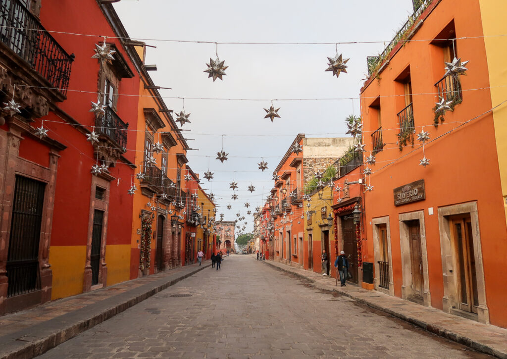 Cobblestone street in San Miguel de Allende lined with red and orange buildings