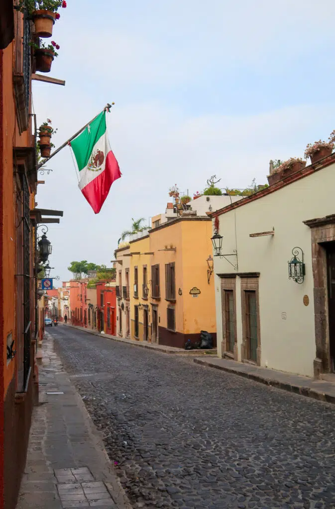 A quaint street in San Miguel de Allende with the Mexican flag blowing in the wind