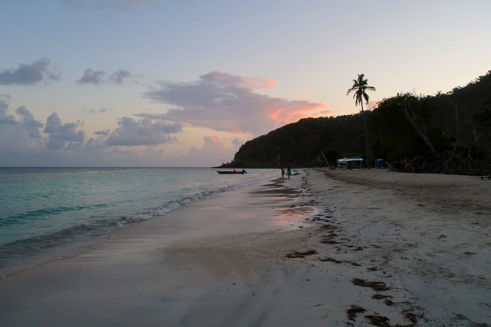 Beautiful silhouettes of mountains, trees, and people on the beach at sunset