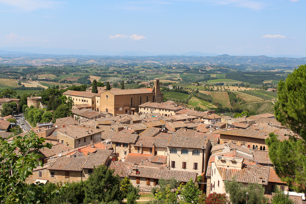 A beautiful view of a small town in Tuscany with rolling hills and vineyards beyond