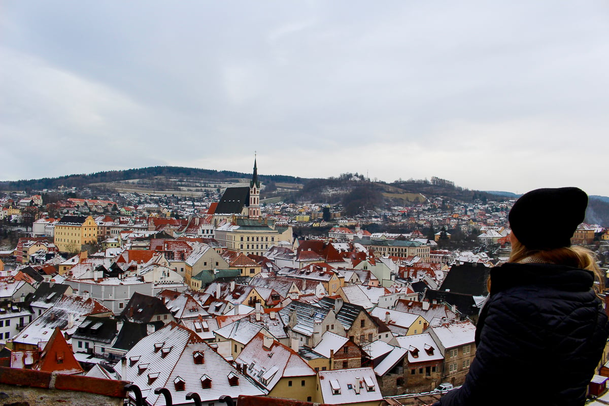 Maddy looking out from a balcony and enjoying the view of the town. Taking a day trip to Český Krumlov is one of the best things to do in Europe.