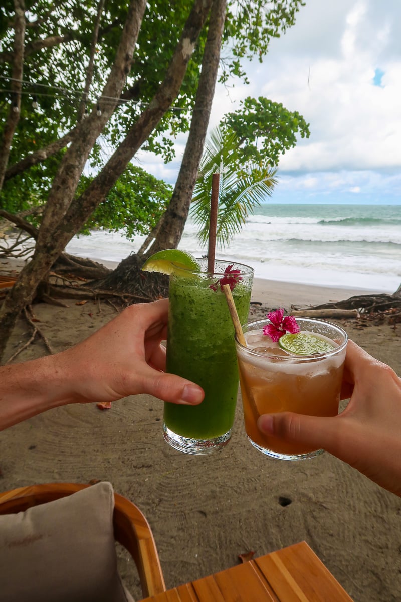 Holding two glasses of cocktails while relaxing in Manuel Antonio