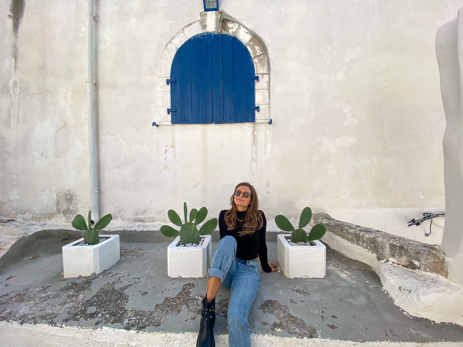 Melanie, blogger, sitting between potted cacti plants in Peschici, Puglia