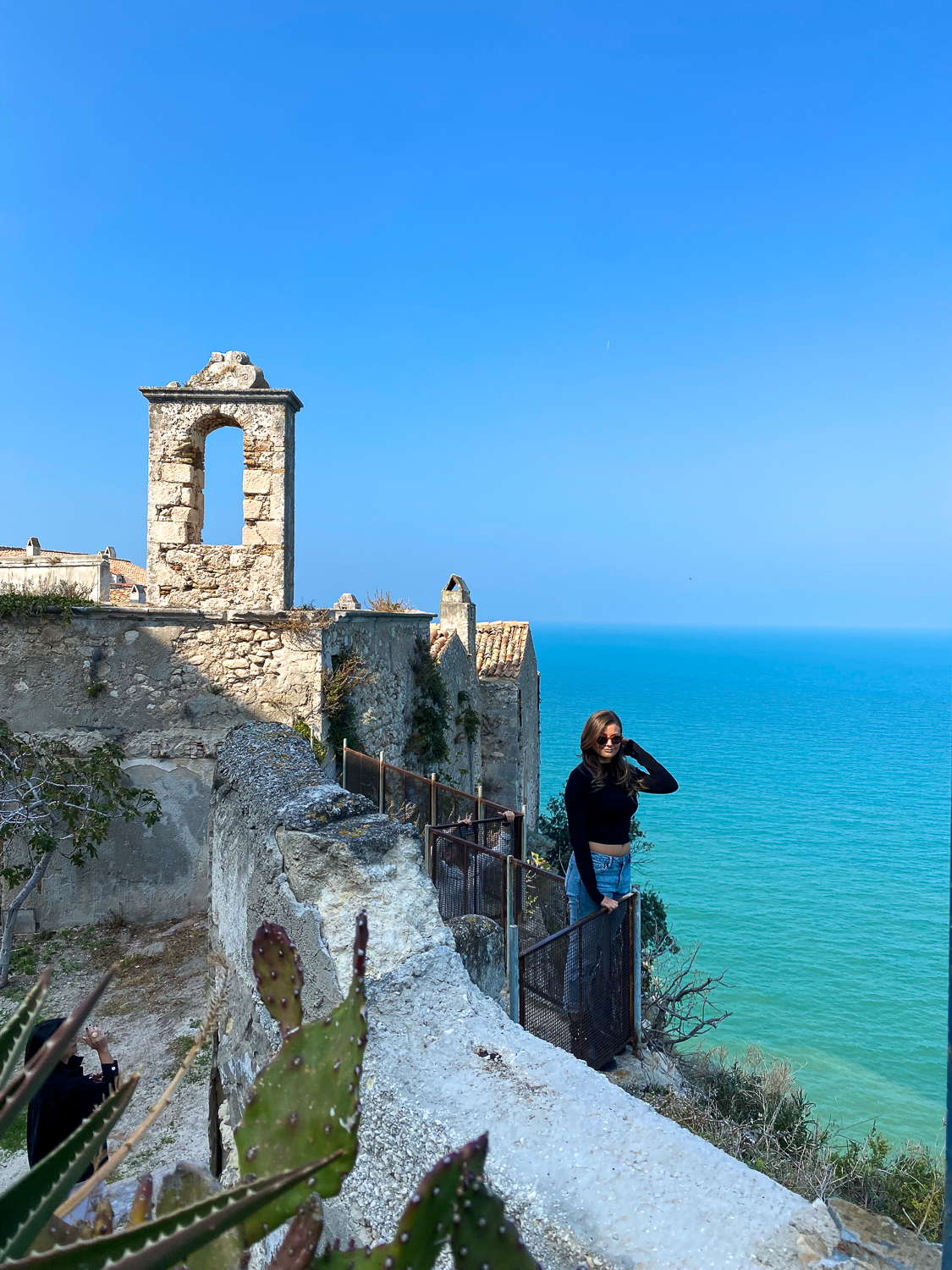 Melanie standing on a viewpoint by the sea in Peschici - a must-add in your Puglia road trip itinerary