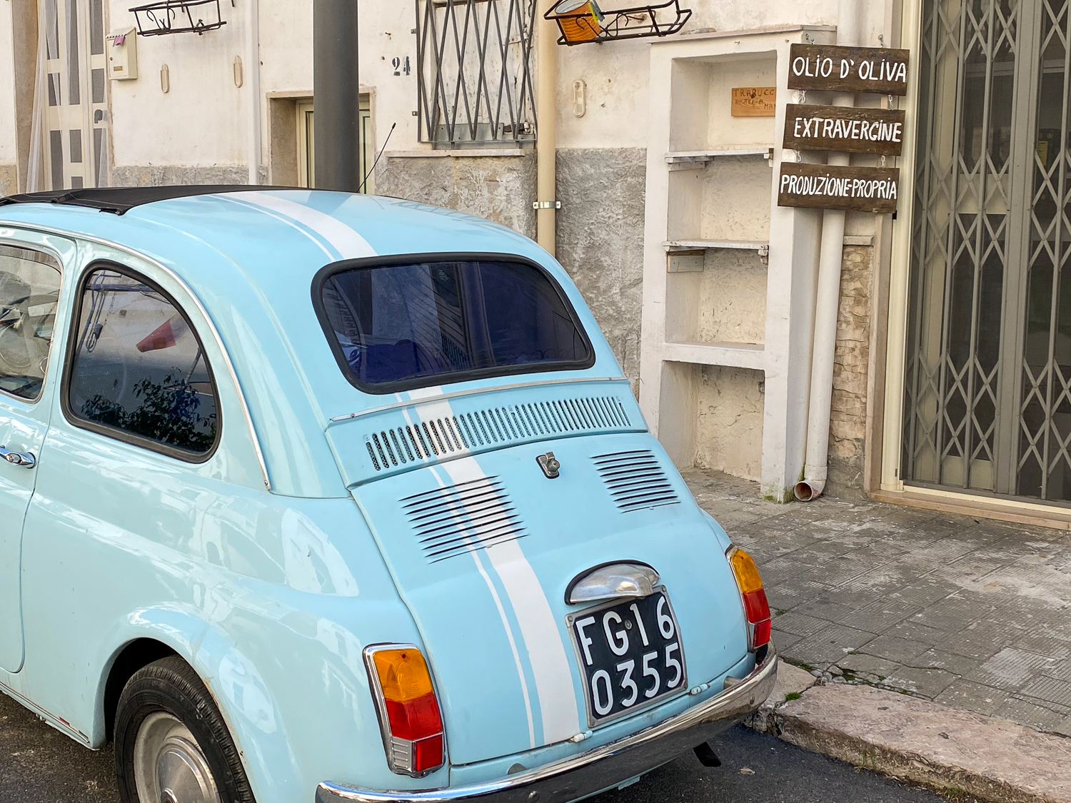 Blue car by a sidewalk in Peschici - a must-add in your Puglia road trip itinerary