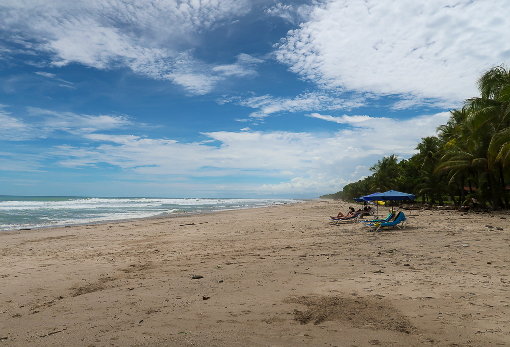 Lounge chairs with beach umbrellas on a beach in Santa Teresa - a must-visit place to complete the best Costa Rica itinerary