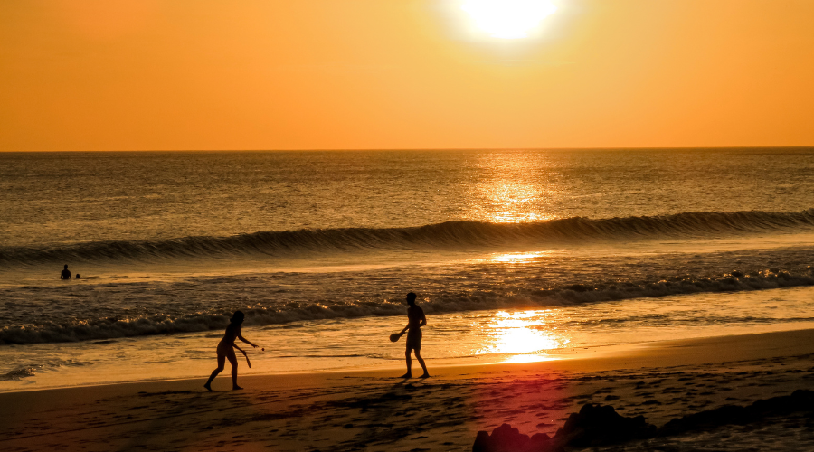 Silhouettes of people hanging out and surfing in a Popoyo beach at sunset. Surfing is one of the things to do in Popoyo Nicaragua.