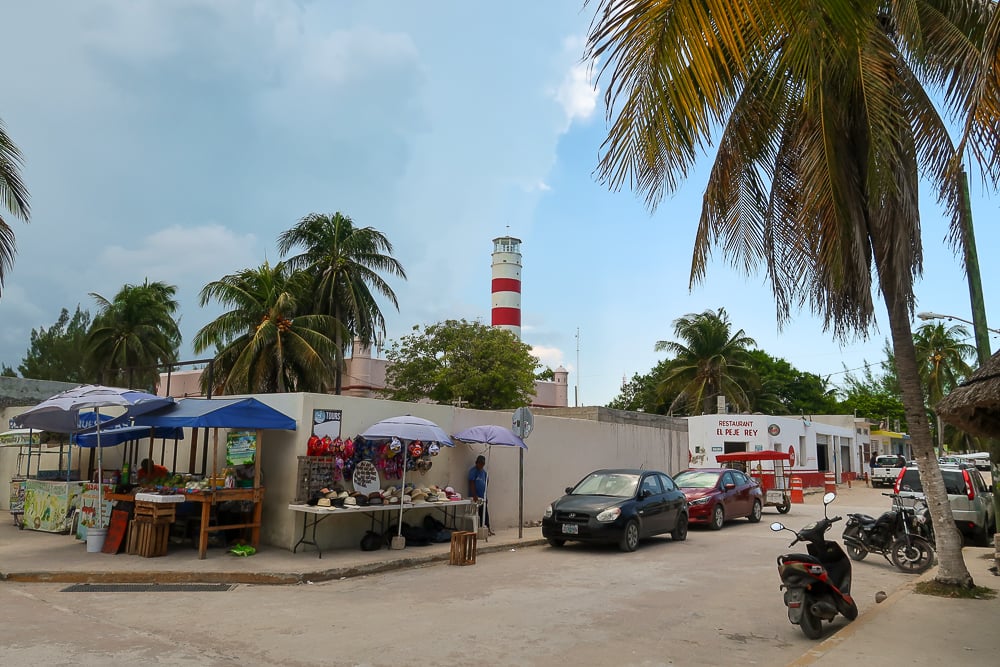 Street vendors and parked vehicles with a view of the lighthouse in Sisal, a magical town in Yucatan