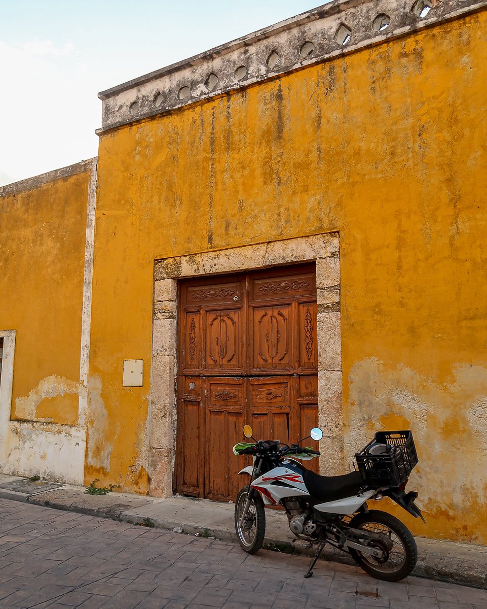 Motorcycle parked by a yellow building in Izamal, Mexico