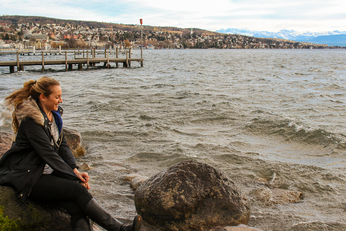 Maddy at the lake, sitting on a rock, while spending two days in Zurich
