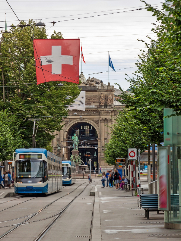 Swiss flag and trams on a busy street in Zurich