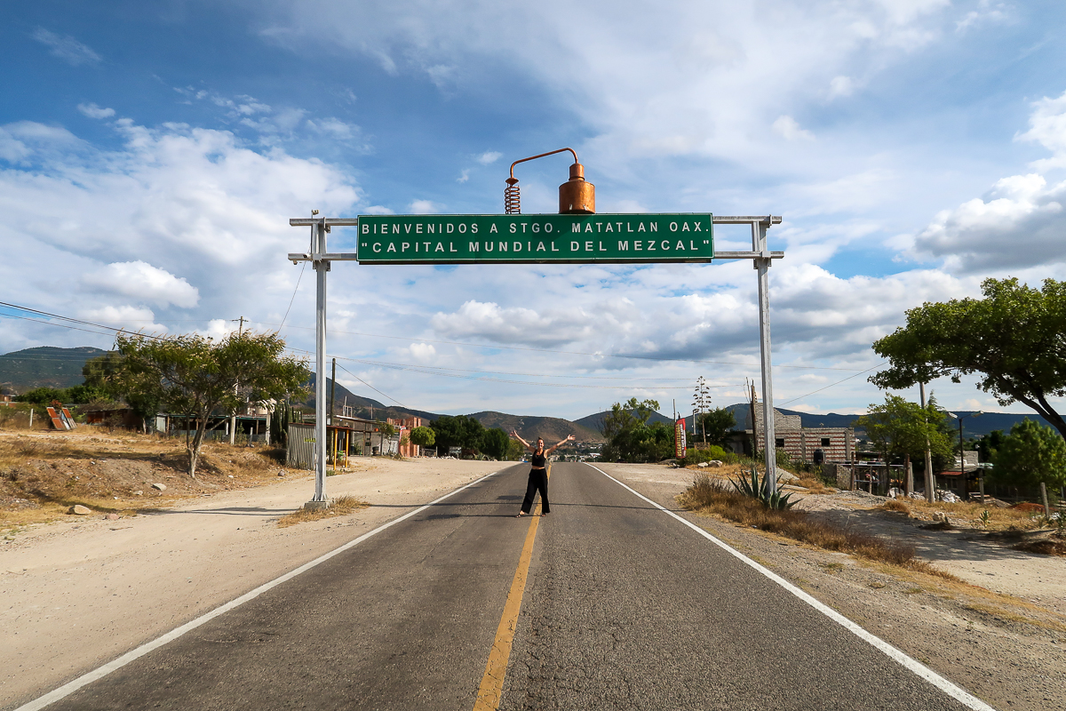 Maddy, a Mexico digital nomad, under the road signage of Santiago Matatlan