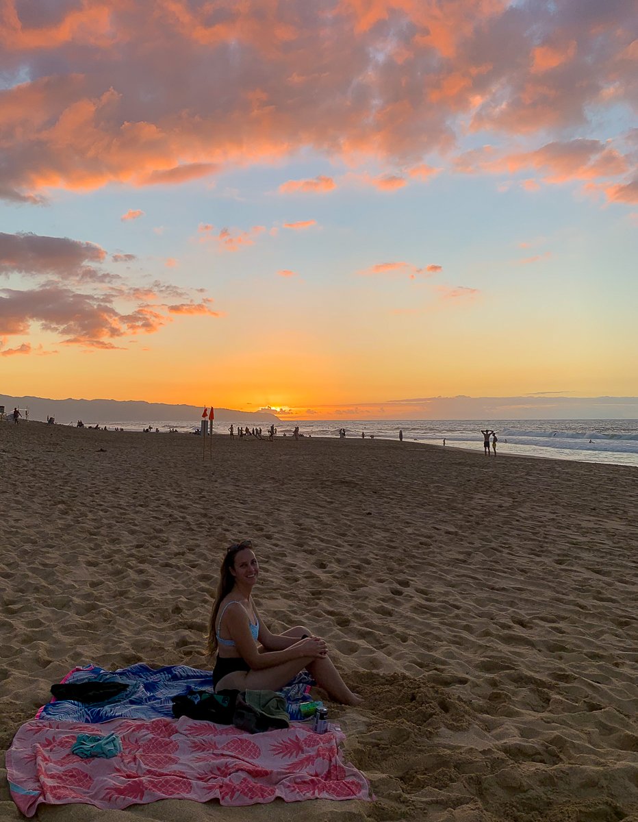 Maddy sitting on the sandy beach of North Shore at sunset. If you're looking for Hawaii vacation ideas, Oahu is definitely one of the best choices.