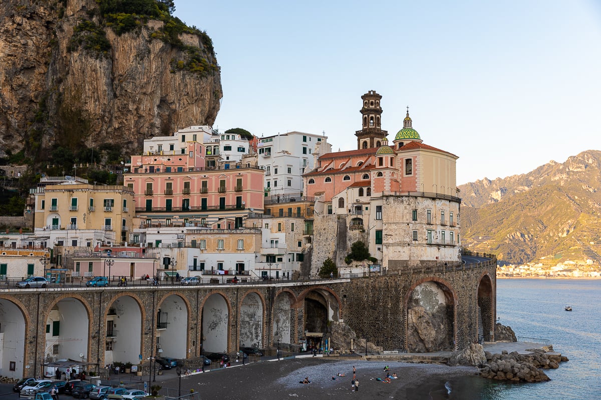 Ancient stone archways below the pastel-colored houses of Atrani, one of the Amalfi Coast towns you must visit