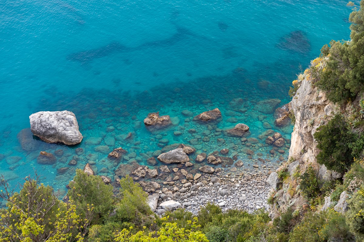 A gorgeous rocky cliffside beach with crystal-clear water, near the town of Amalfi