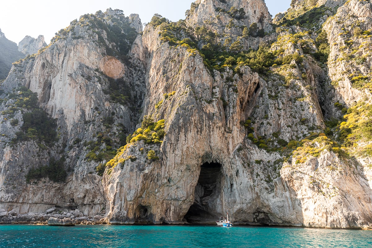 A rugged limestone island with a boat in the sea in front of it