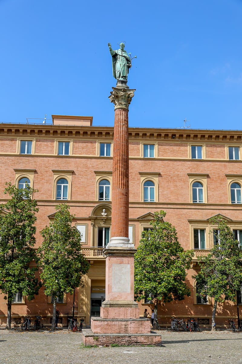 A red brick building with a statue in front of it on a sunny day