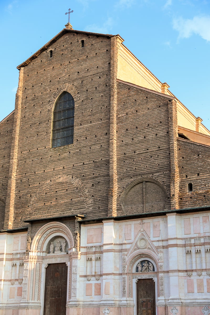 The front of the Basilica di San Petronio in Bologna, Italy - it is partly brick and partly pink and white tile.