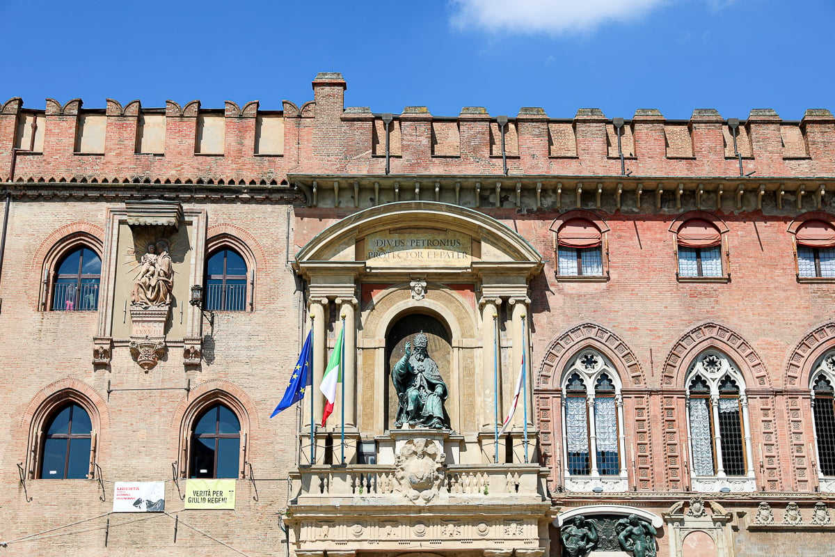 A red brick building, adorned with statues, in the Piazza Maggiore in Bologna, Italy