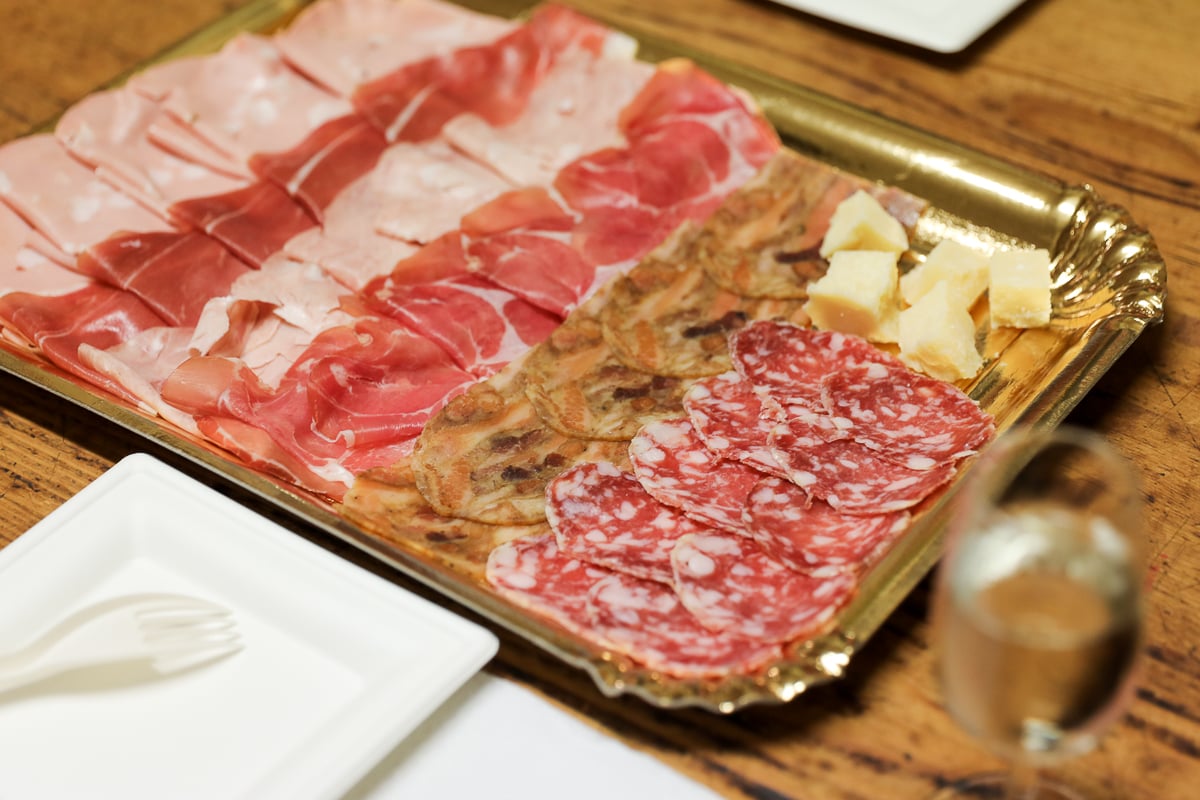 A platter of different Italian cold cuts with some chunks of parmesan cheese too