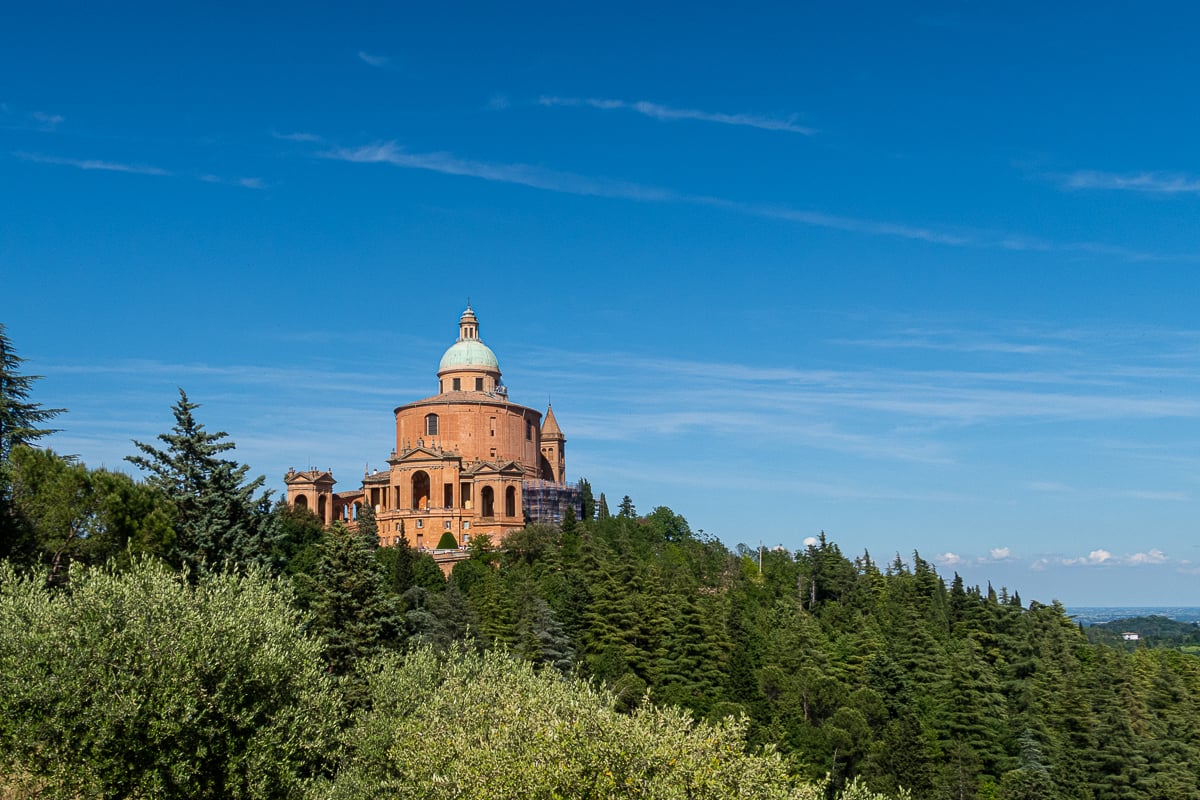 the Santuario di Madonna di San Luca peeking out from dozens of trees on a sunny day