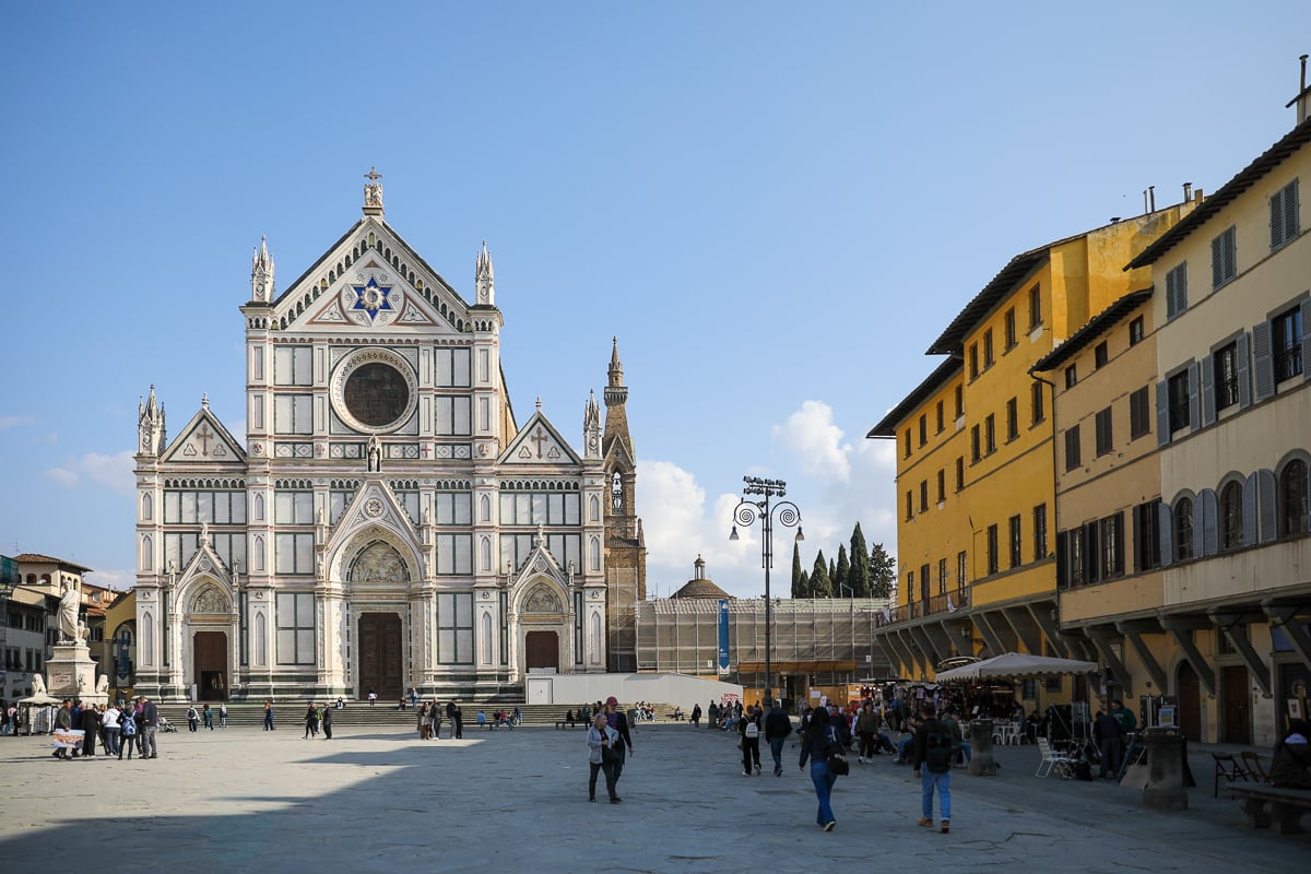 The facade of the Basilica di Santa Croce, with people strolling through the piazza
