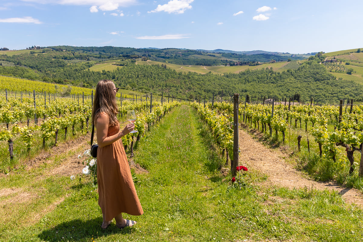 Maddy standing in a vineyard in Tuscany on a sunny day holding a glass of wine