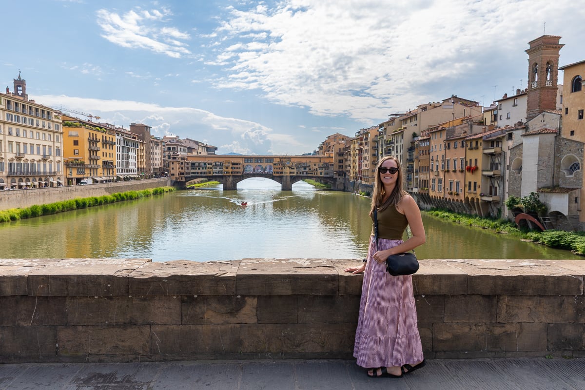 Maddy standing on a bridge in Florence with the Ponte Vecchio and Arno River in the background