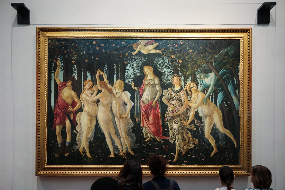 Five people admiring a painting called Primavera by Botticelli in the Uffizi Gallery in Florence