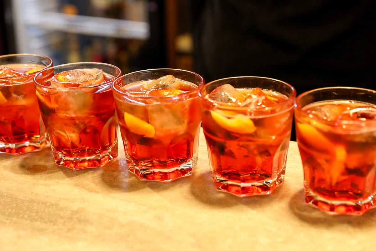 Five negroni cocktails sitting on a bar
