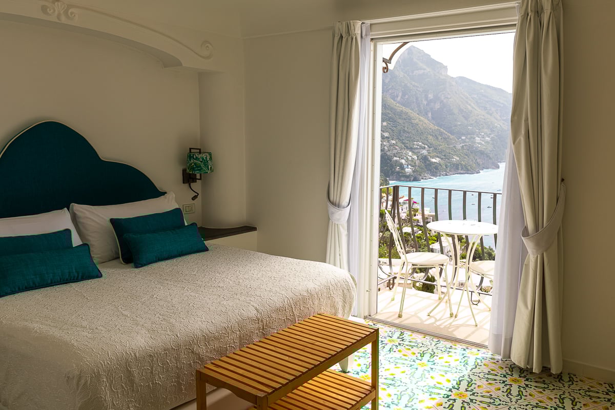 Cozy bedroom with a terrace overlooking the sea. In this Positano travel guide, you'll find the best hotels you can stay in during your visit.