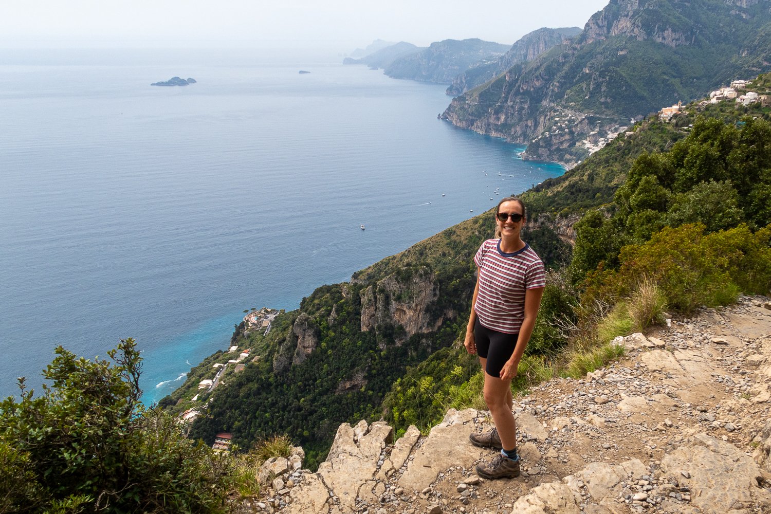 Maddy hiking the trail of the Path of the Gods with a view of the sea behind her
