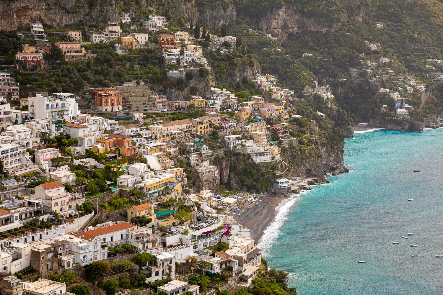 A view of the seaside village of Positano with bright turquoise water and colorful buildings.