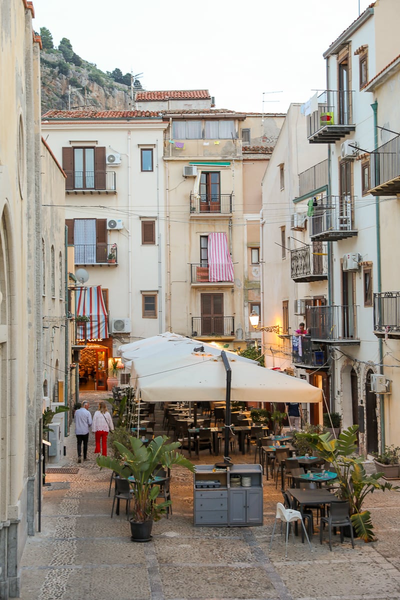 Outdoor restaurant tables between buildings in Cefalu