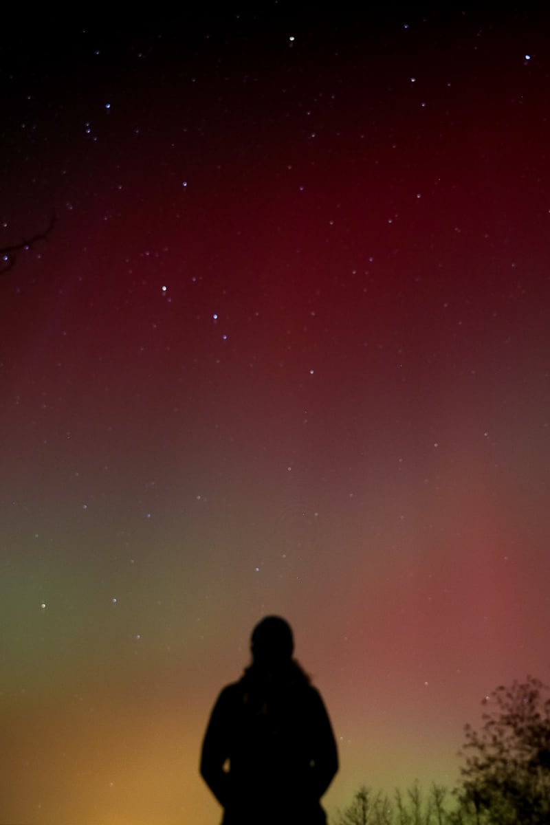 Maddy's silhouette looking up the colorful sky in Iceland