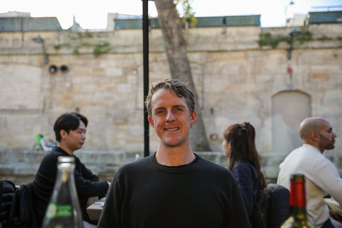 Cacey smiling while on the river cruise in Paris, with the banks of the Seine and other diners in the background.