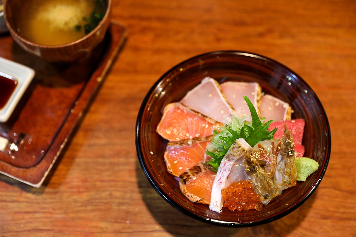Colorful kaisendon rice bowl topped with fresh sashimi, salmon roe, and gold leaf, served with miso soup at a seafood restaurant in Kanazawa.