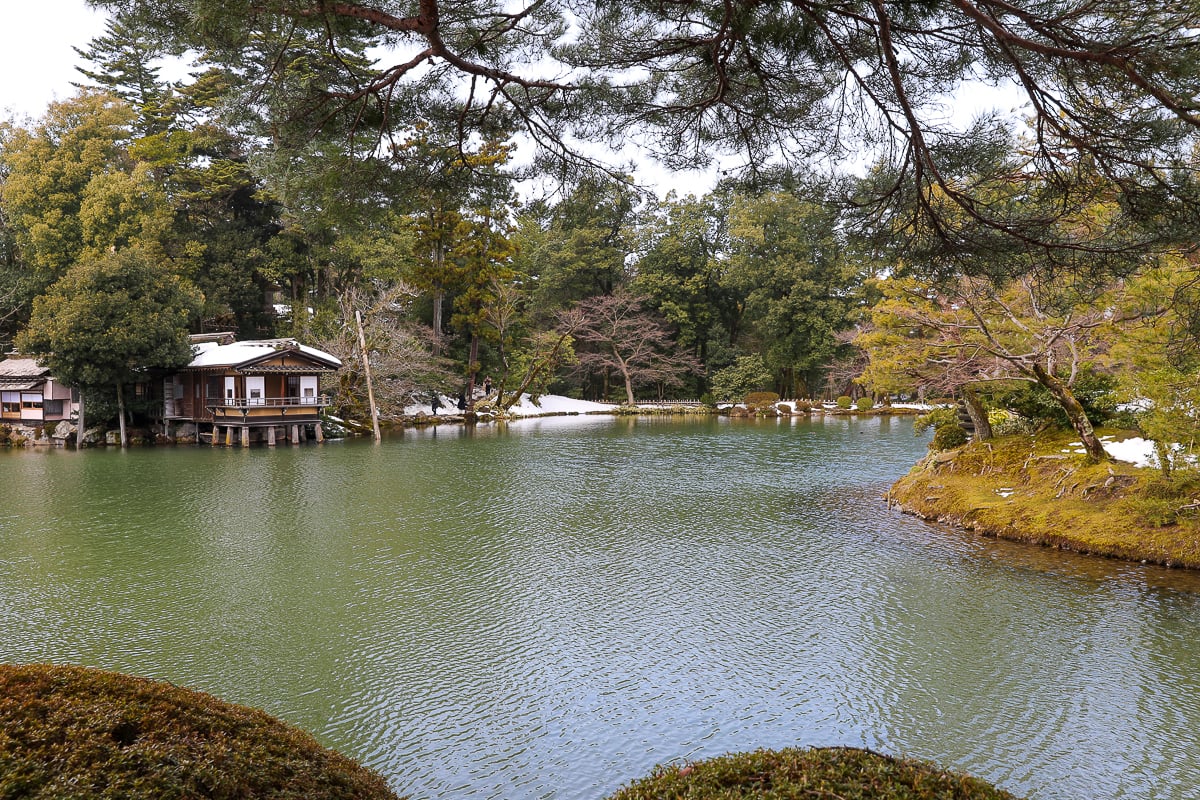 Tranquil pond and traditional teahouse surrounded by pine trees and snow at Kenrokuen Garden, one of Japan’s most beautiful landscapes in Kanazawa.