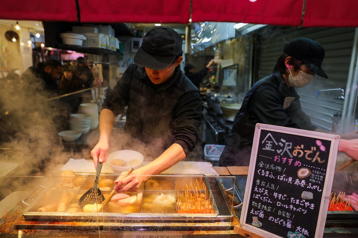 Steam rising from a bubbling pot of oden—fish cakes, eggs, daikon, and tofu—served by a street vendor at Omicho Market in Kanazawa.