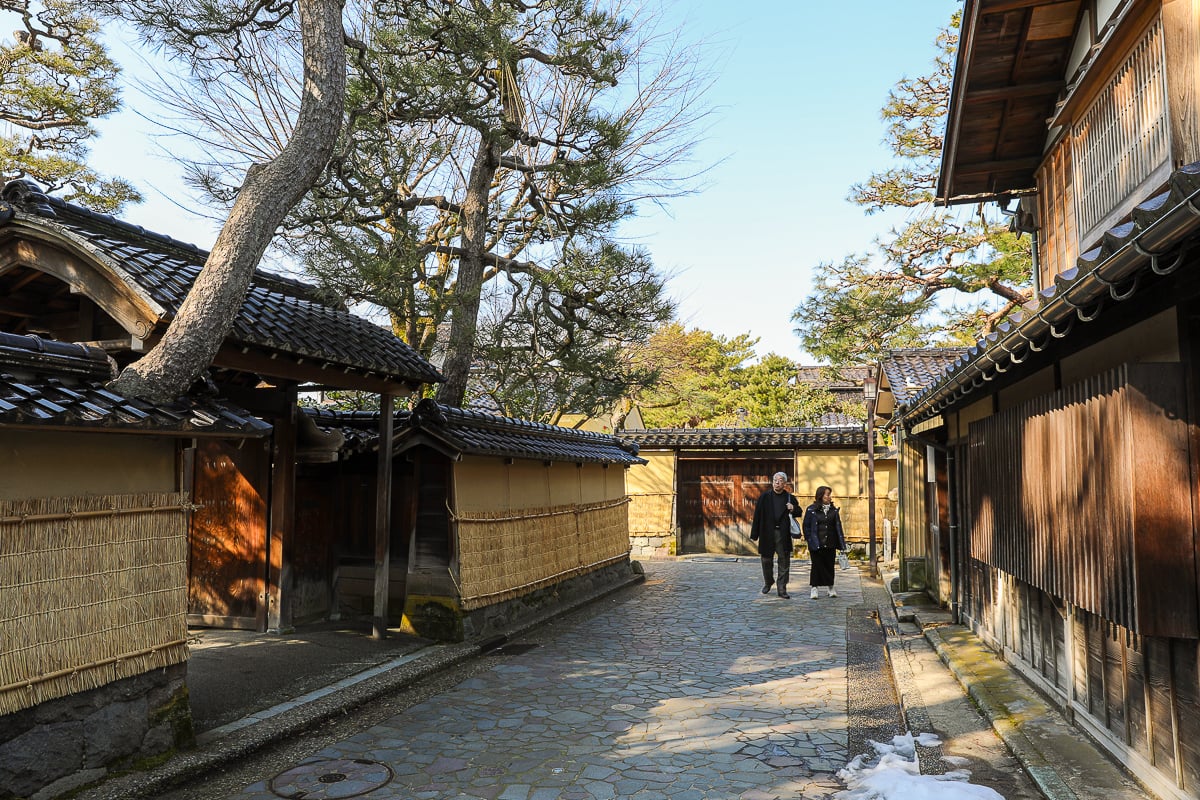 Traditional wooden houses and narrow stone lanes in Kanazawa’s Nagamachi Samurai District, with locals strolling under winter sunlight.