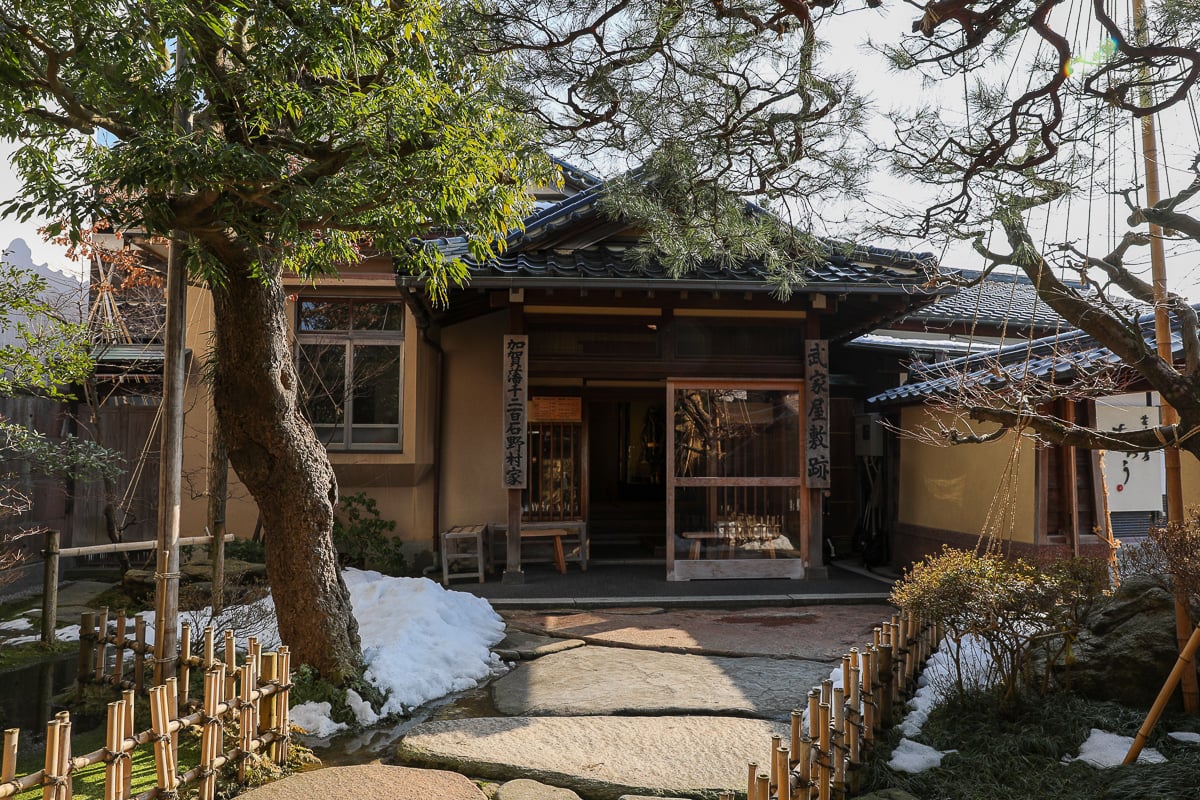 Entrance to a preserved samurai residence surrounded by a peaceful garden and snow patches in Kanazawa’s Nagamachi district.