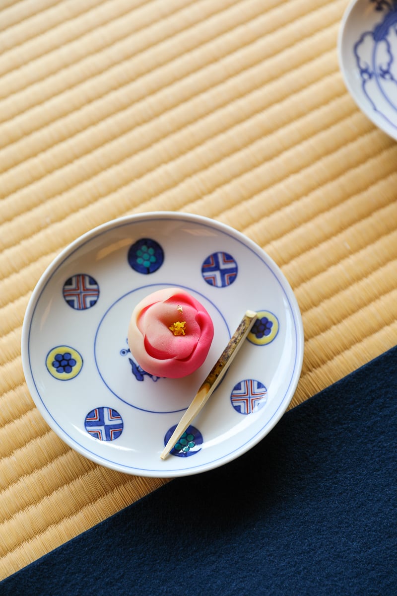 Delicate pink and white wagashi sweet on a porcelain plate with Japanese patterns, served during a traditional tea ceremony in Kanazawa, Japan.