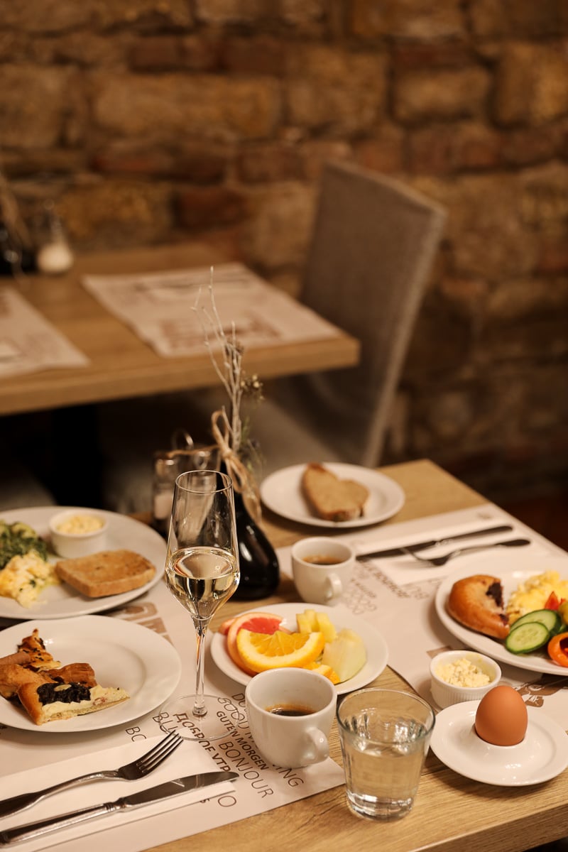 Traditional Czech hotel breakfast with eggs, bread, fruit, and prosecco at Hotel Rott in Prague