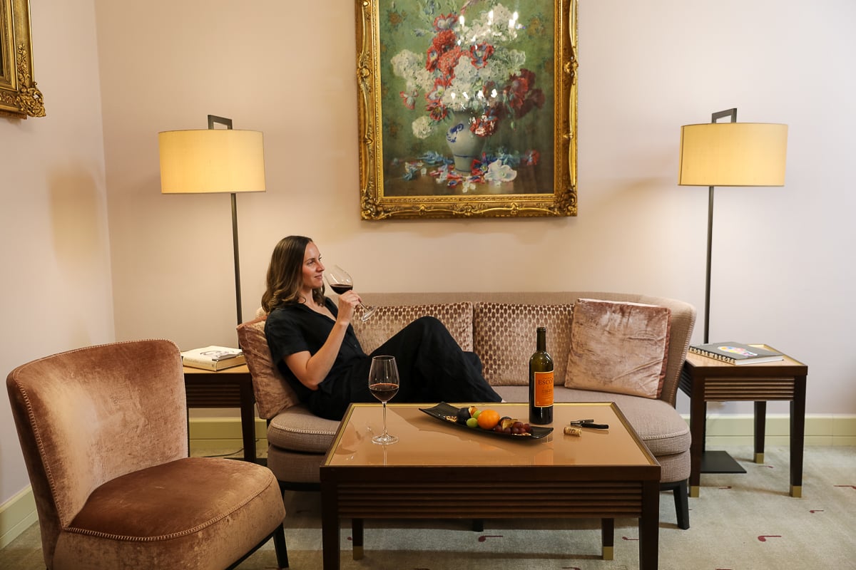 Maddy relaxing with a glass of wine in a sitting area of her guest room at the Aria Hotel Prague in Malá Strana
